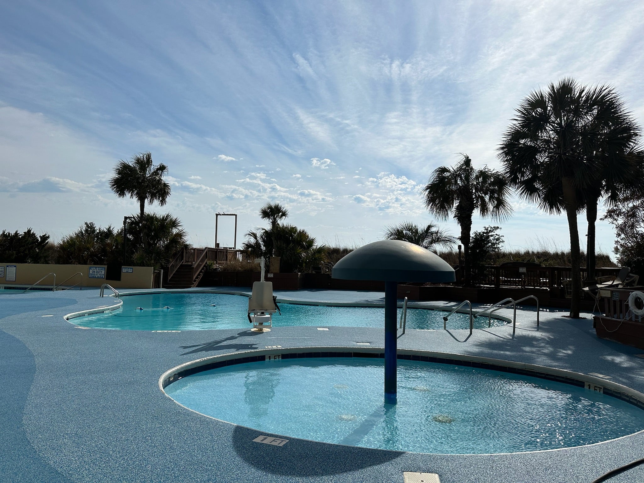 Myrtle Beach Cove - After - with rubber surfacing - Outdoor pool area with palm trees and a clear sky