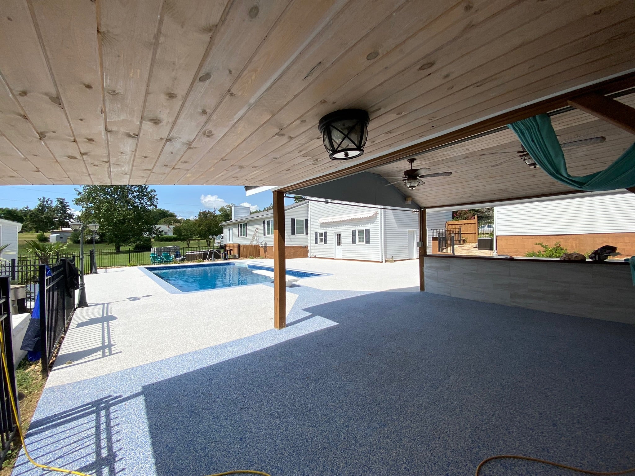 Residential - Covered patio area with pool and house in the background. After image - White / Cream Rubber Surfacing installed.