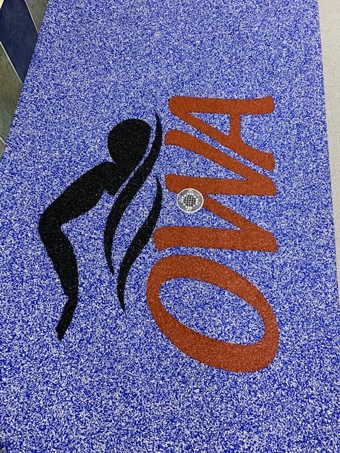 OWA Aquatic Center - After Rubber Surfacing Installation - Blue textured mat with a black silhouette and orange 'OWA' logo.