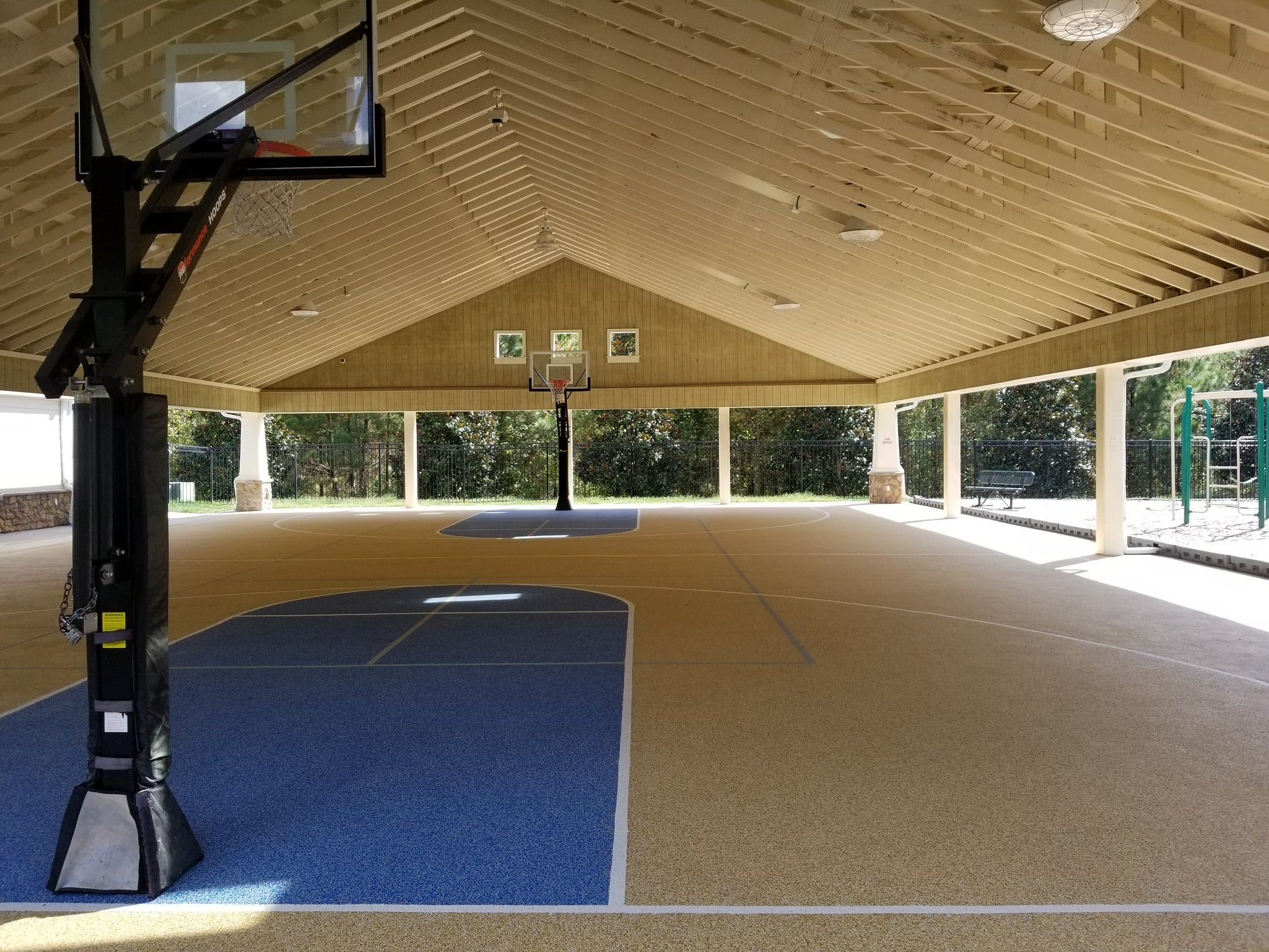 Indoor basketball court with rubber surfacing - hoop and blue and beige rubber flooring