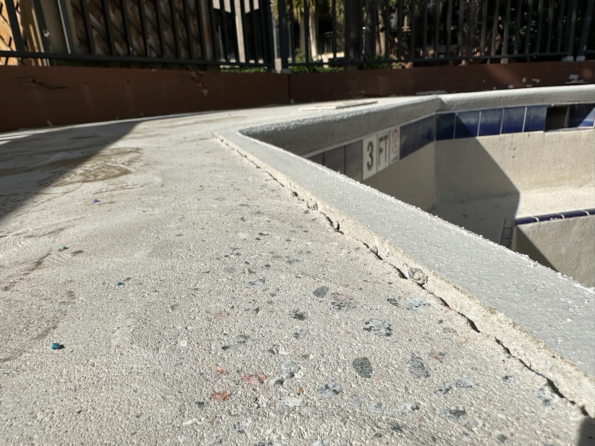Pool without rubber surfacing - before - Concrete surface with a pool in the background