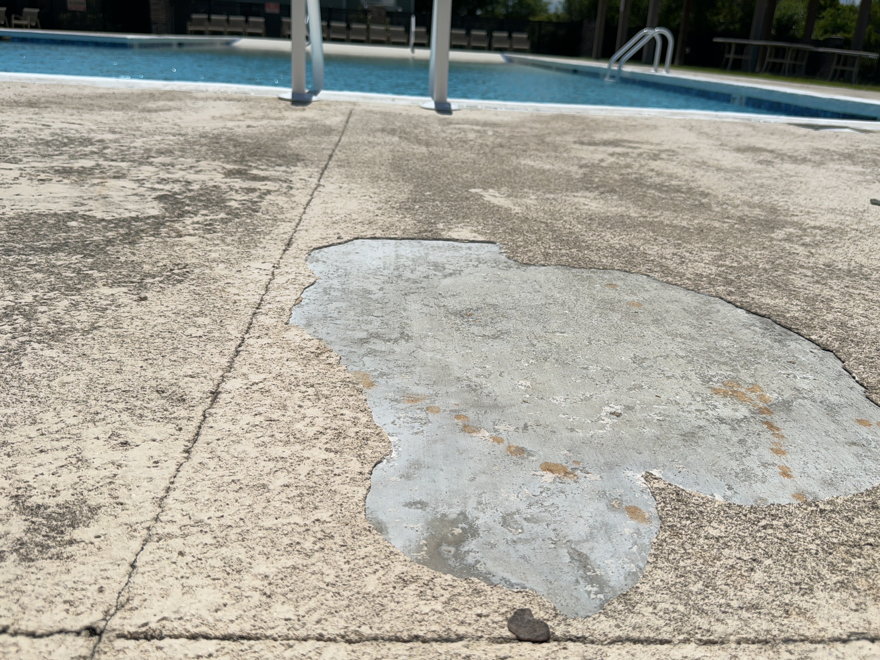 Bay Tree Lakes - HOA - Before Rubber Surfacing Installation - Damaged concrete near a pool with a visible crack