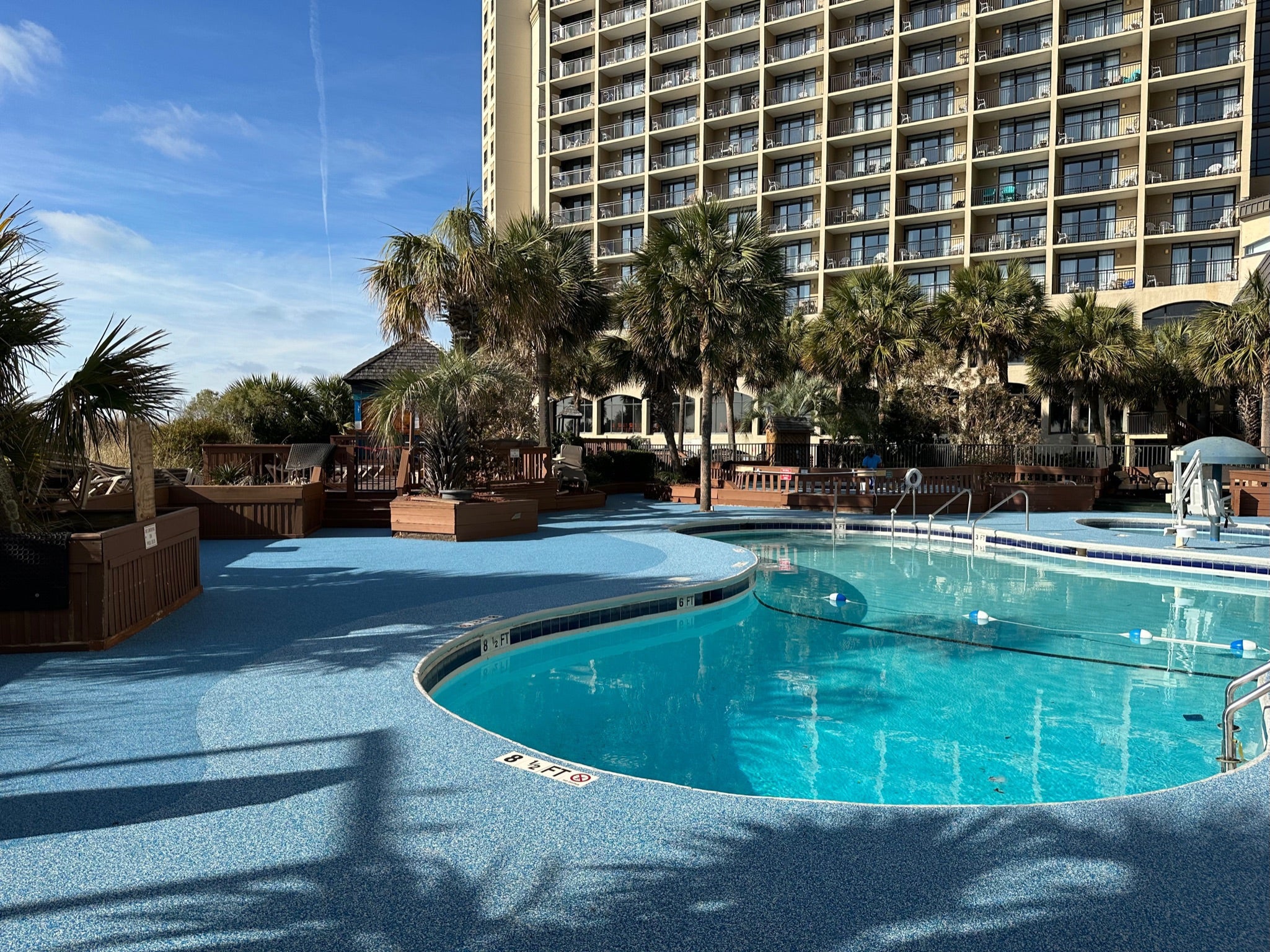 Myrtle Beach Cove - After - with rubber surfacing - Pool area with palm trees and a high-rise building in the background