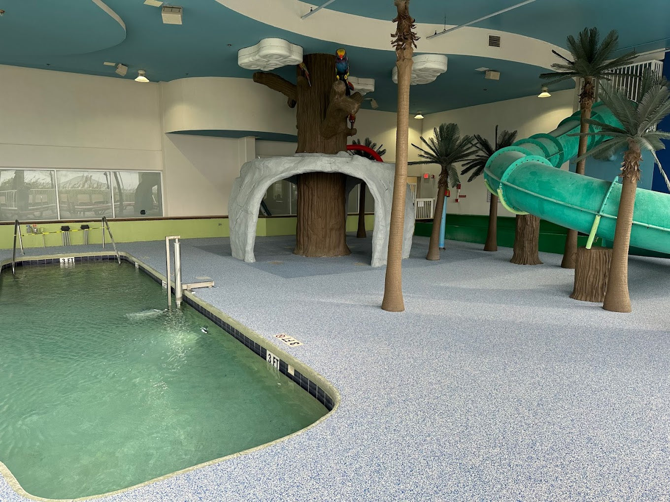 Indoor pool area with slides and tropical decor. Rubber Surfacing is installed.