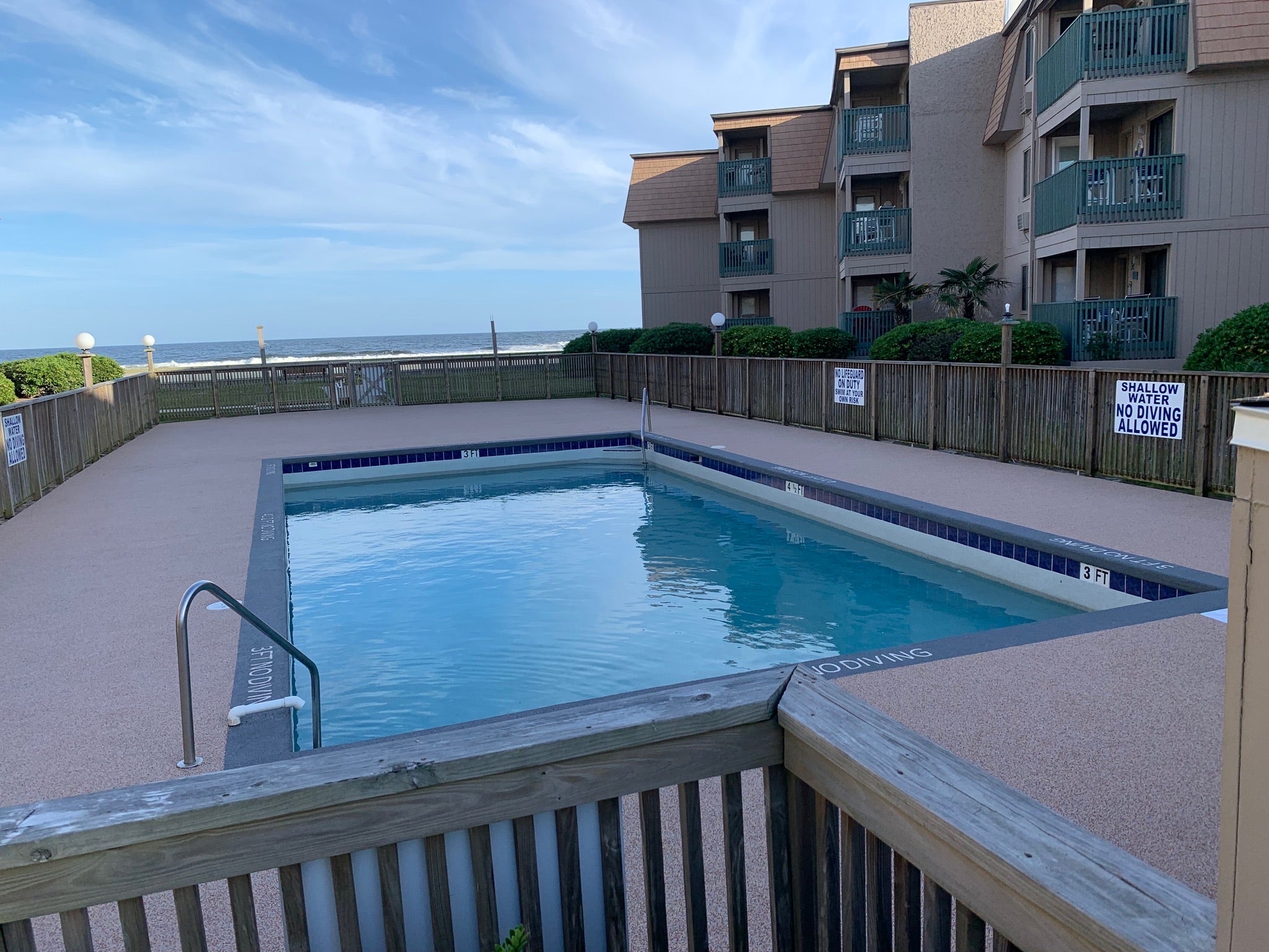 HOA Pool with rubber surfacing - Pool area with ocean view and apartment building in the background