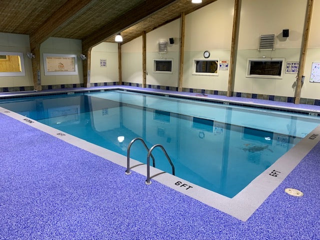 OWA Aquatic Center - After Rubber Surfacing Installation - Indoor pool with blue tiles and white coping, surrounded by walls with framed pictures.