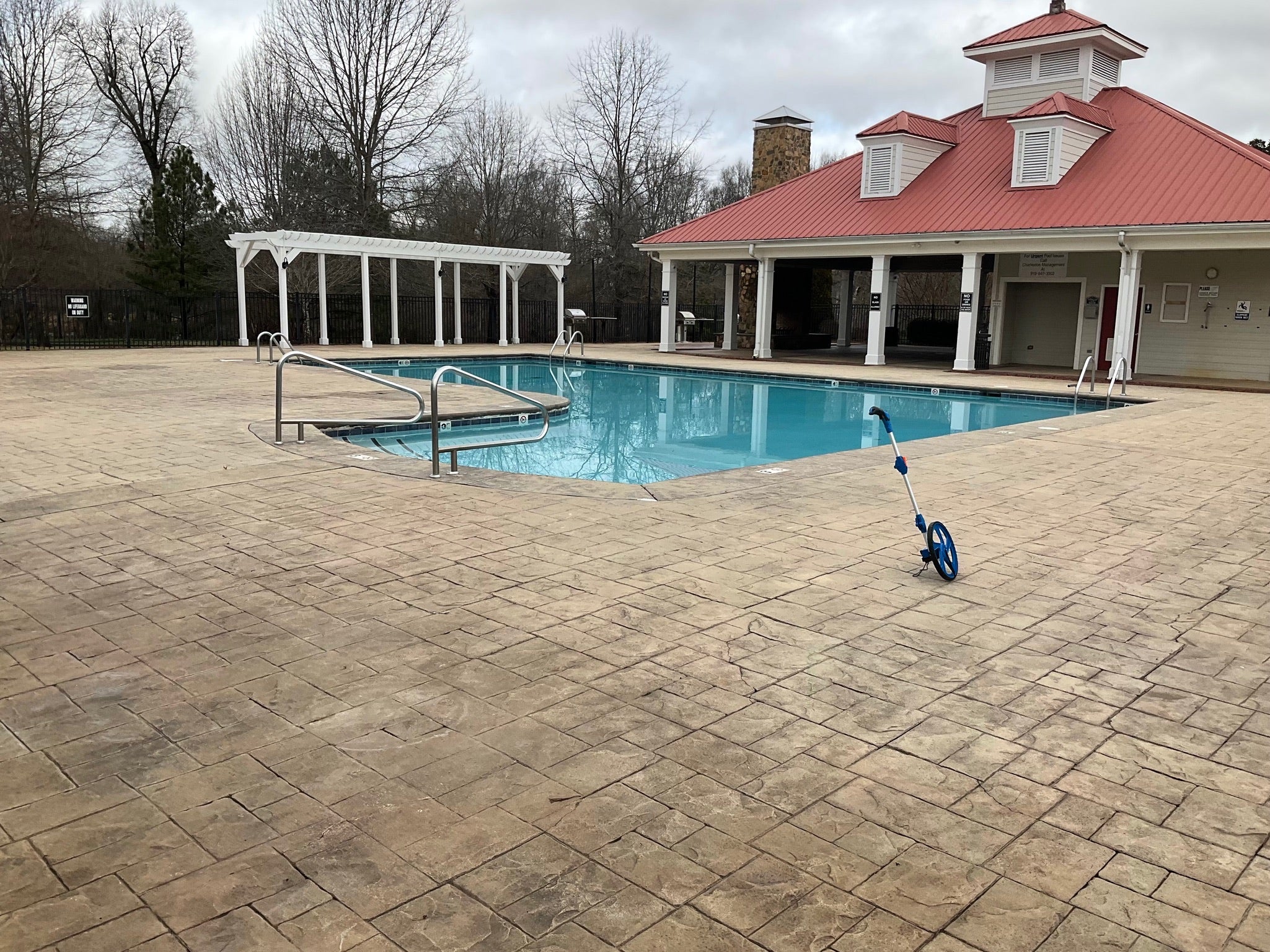 Ashbury Community Project - HOA - No Rubber Surfacing Installation - Before - Pool area with a pool house on a paved patio
