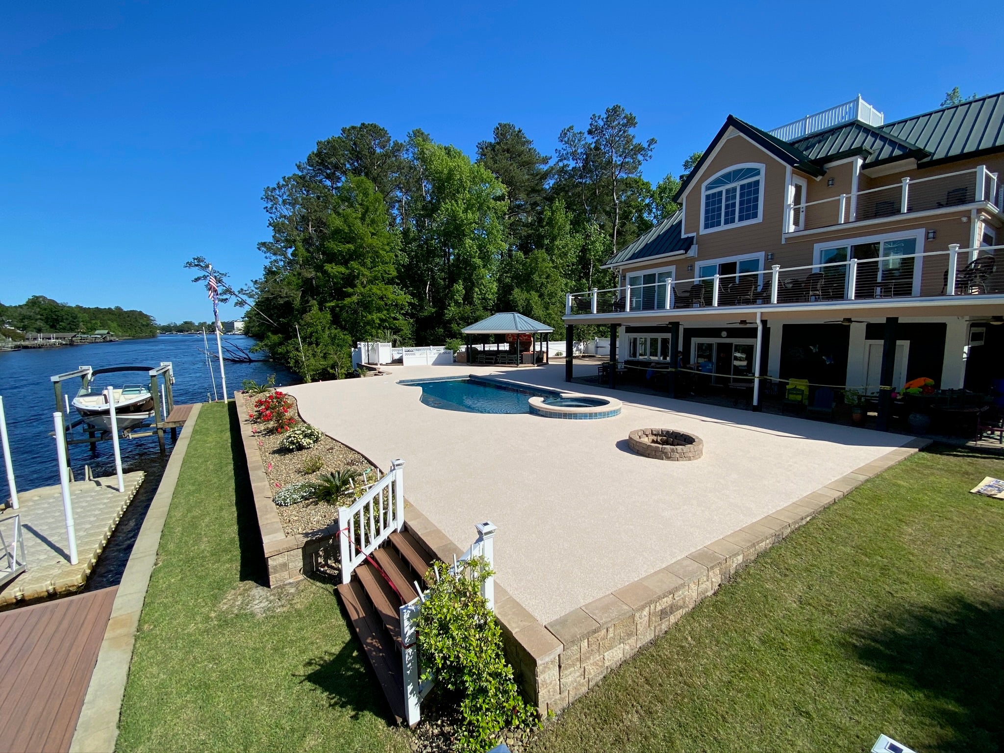 Residential Pool Deck - Luxury waterfront house with pool and dock on a clear day