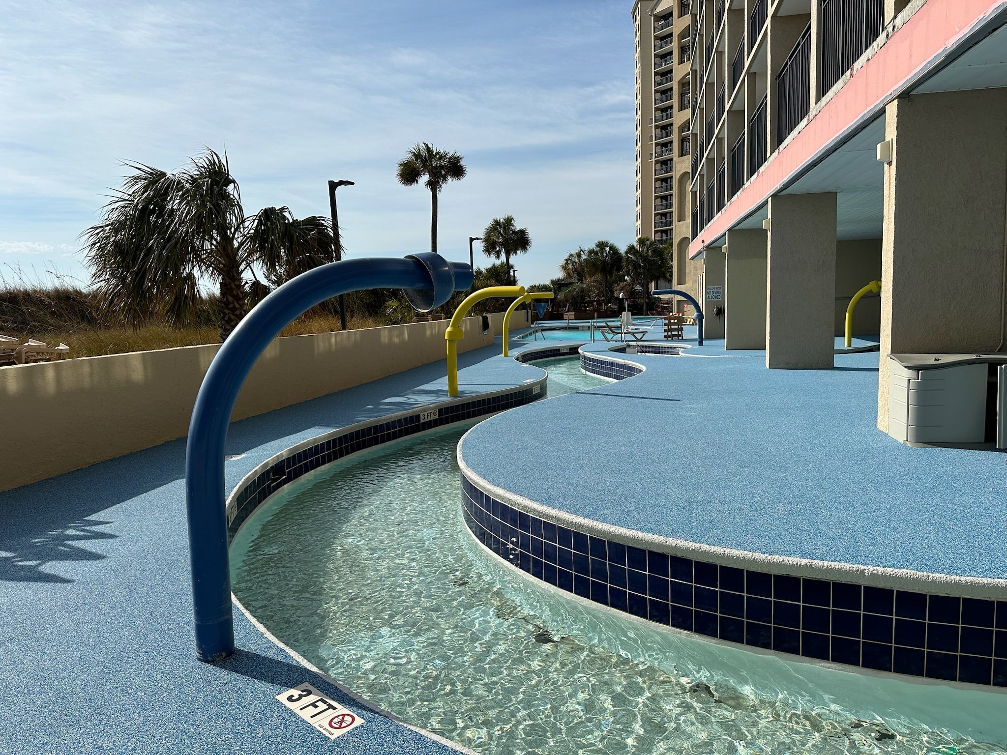 Myrtle Beach Cove - After - with rubber surfacing - Outdoor pool area with blue tiles and a building in the background