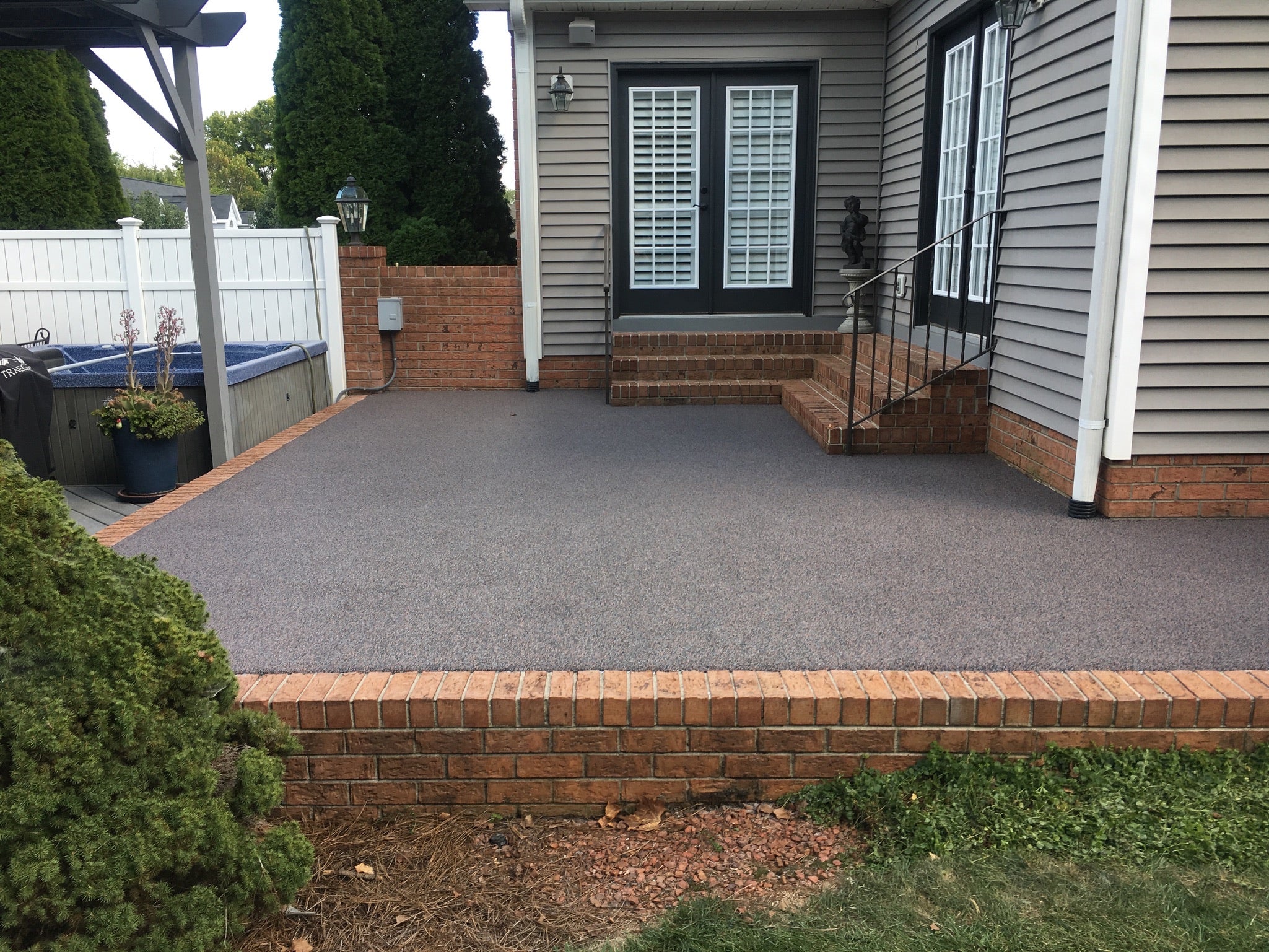 Patio area with rubber surfacing with a house in the background