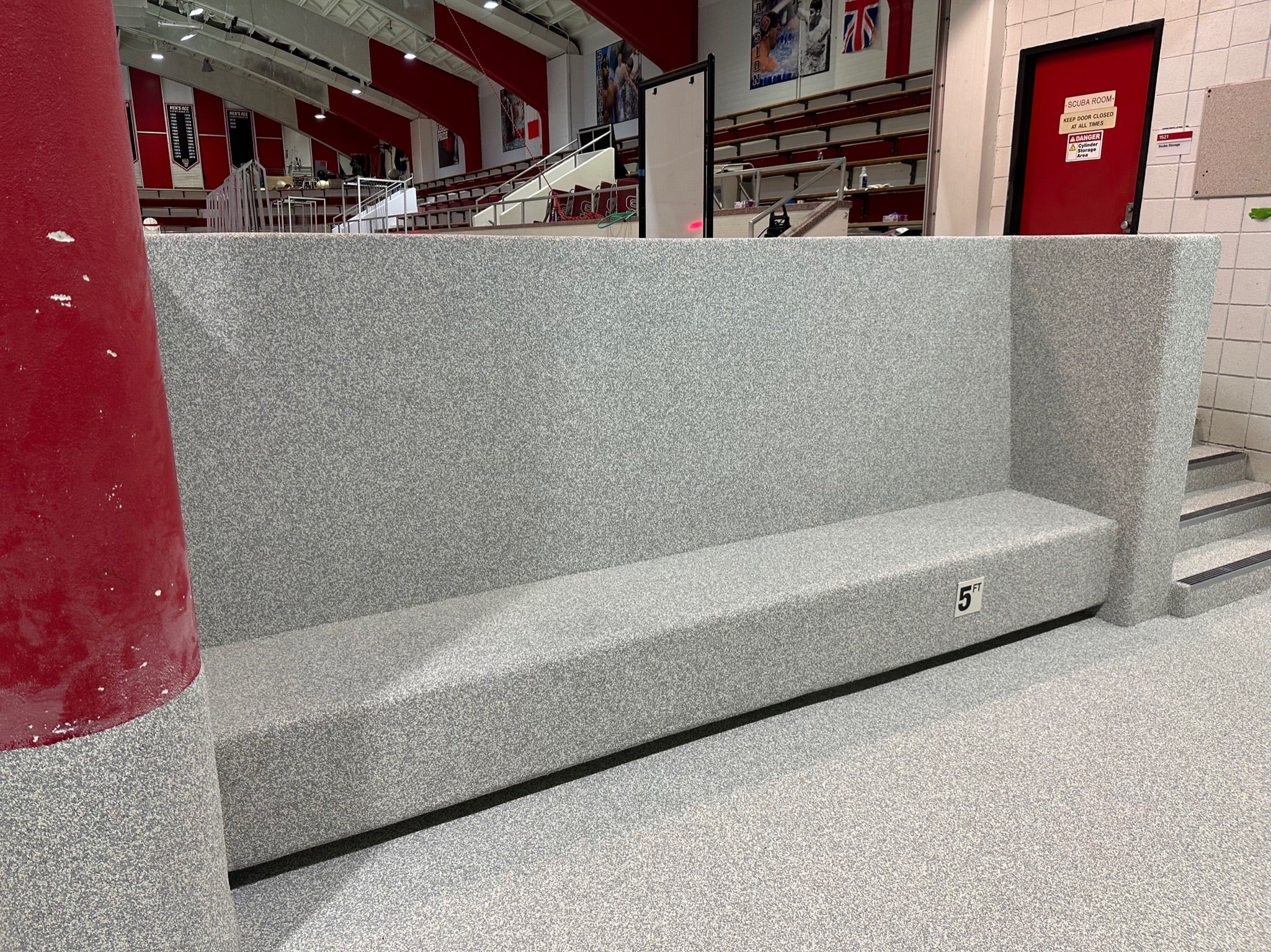 NC State Aquatic Center - After Rubber Surfacing Installation - Gray bench in a public indoor setting with red walls and white floor.
