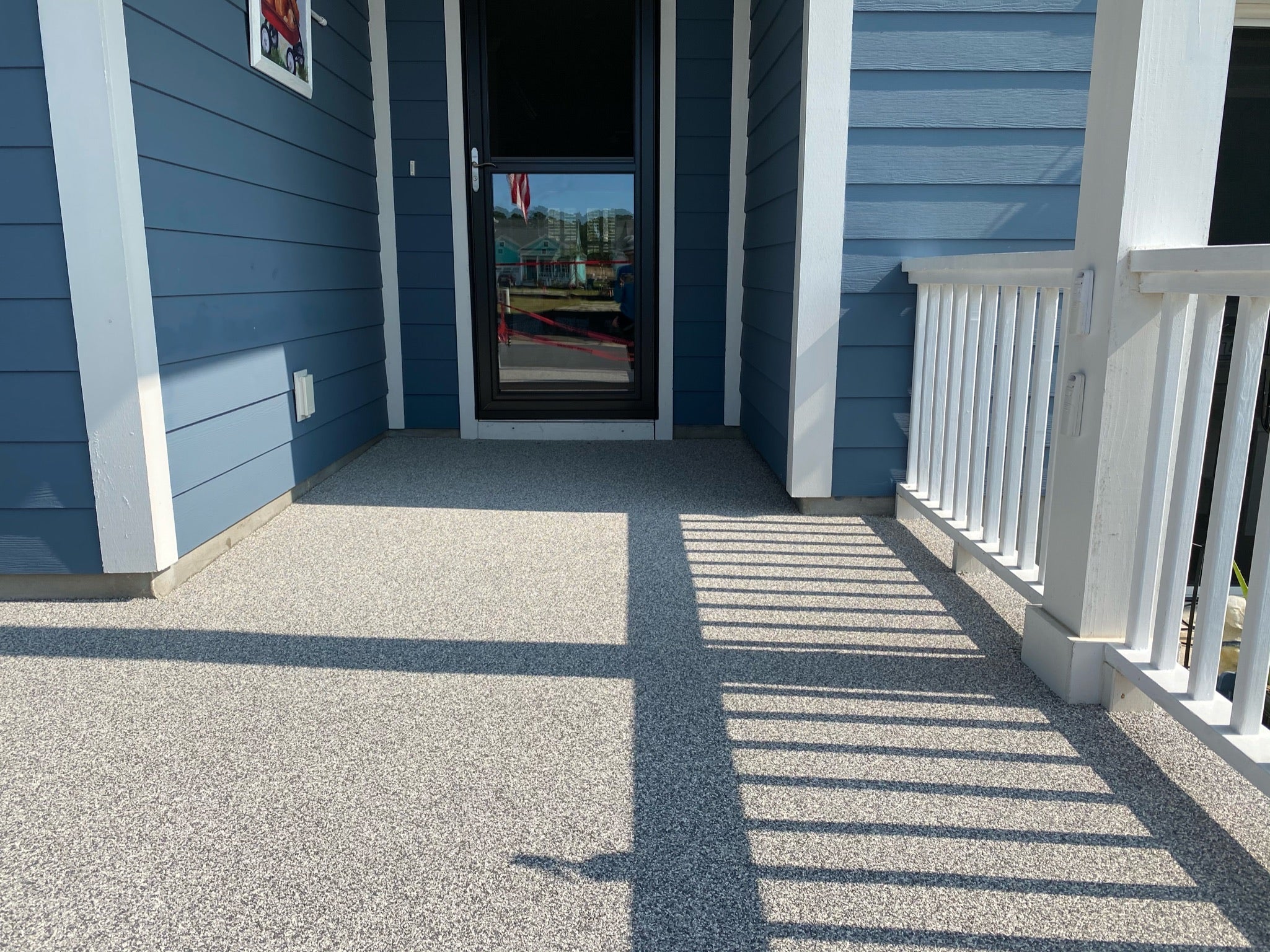 Residential Patio Deck - Blue house exterior with a white door and porch railing