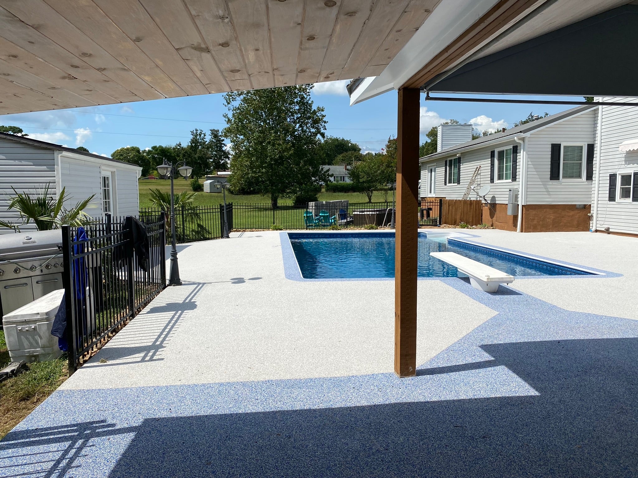 Residential - Backyard with a pool, patio, and surrounding houses. After image - White / Cream Rubber Surfacing installed.