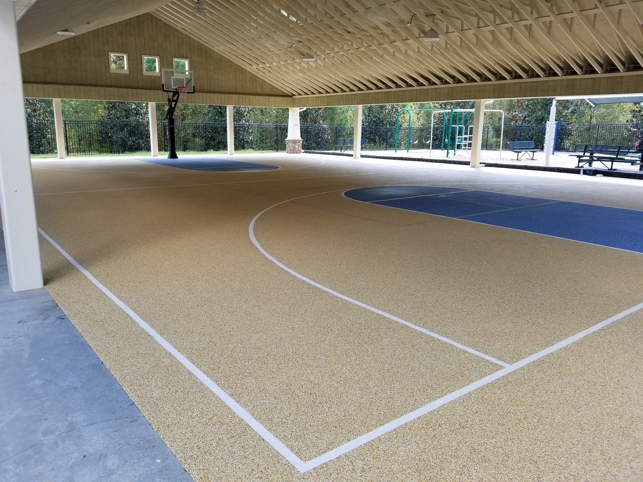 Indoor basketball court with rubber flooring - blue and beige rubber floor under a structure