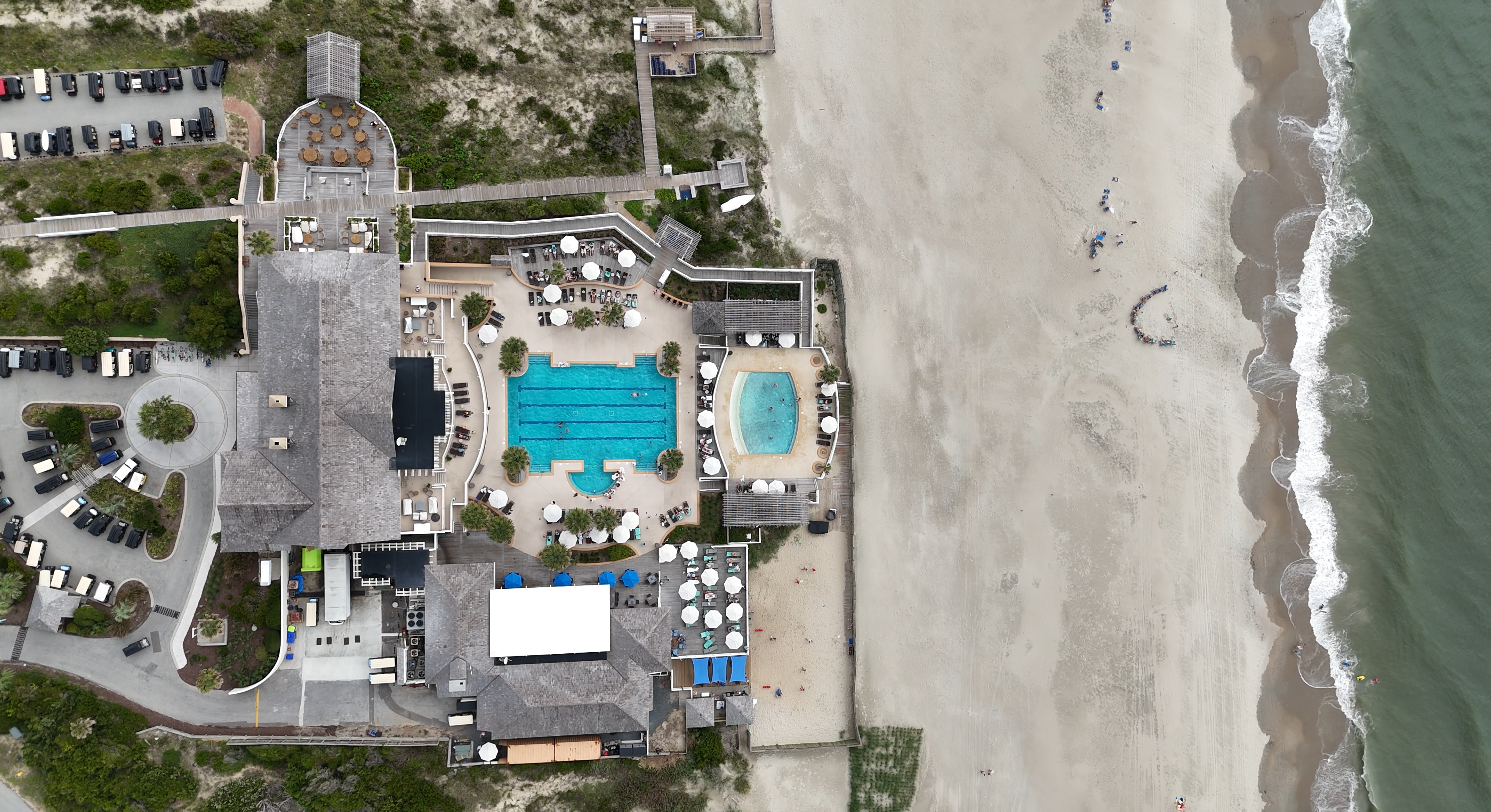 Beach Cove Resort - with rubber surfacing Aerial view of a beachfront resort with pools and parking lot.