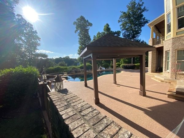 Gazebo next to a pool with a building and trees in the background