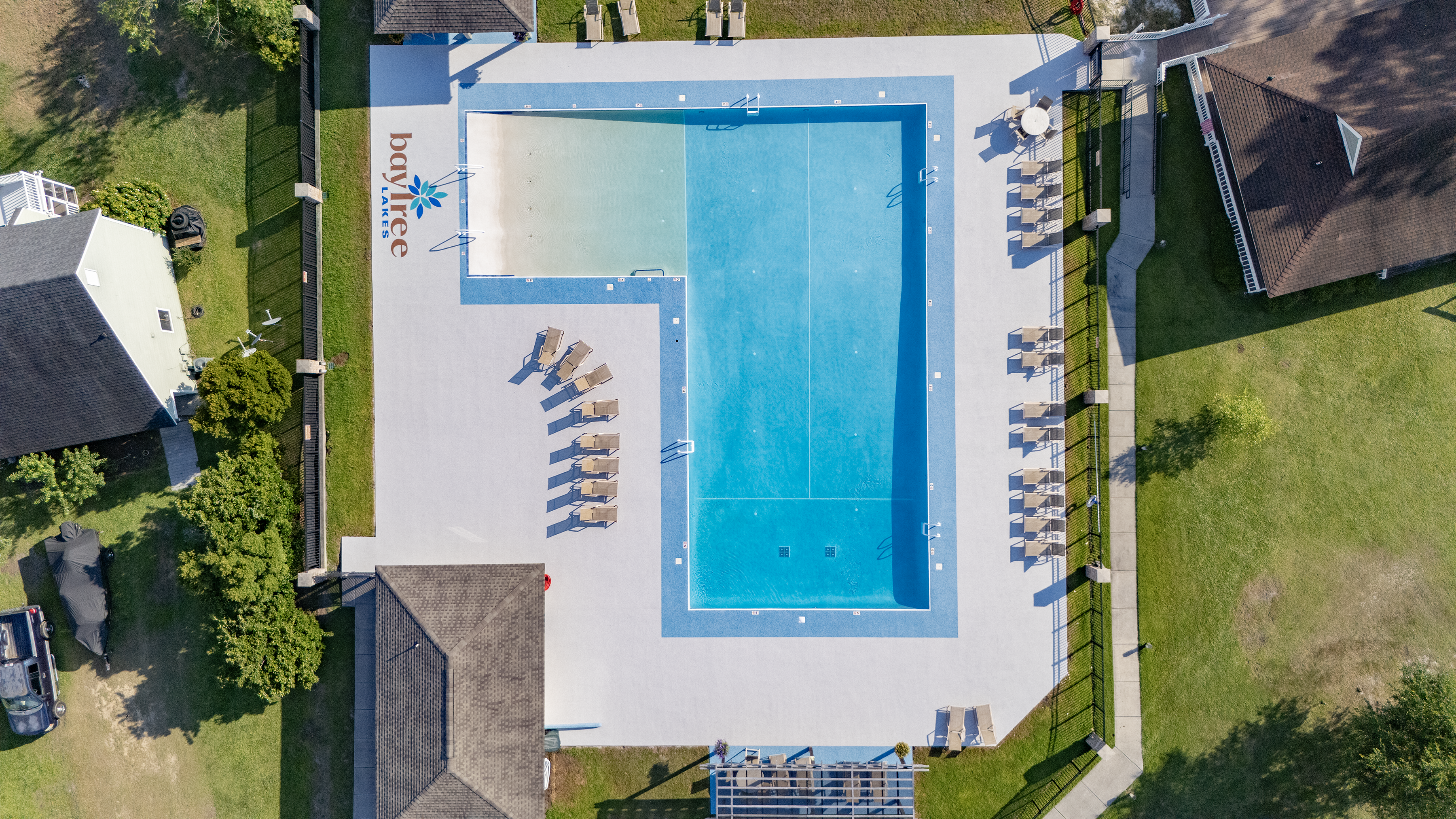 Bay Tree Lakes - HOA - After Rubber Surfacing Installation - Aerial view of a swimming pool with lounge chairs and surrounding area.