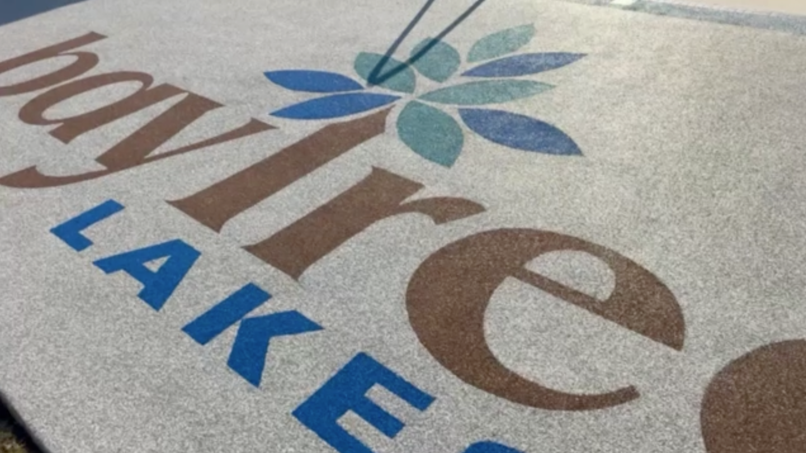 Bay Tree Lakes - HOA - After Rubber Surfacing Installation - Close-up of a logo with 'baytree lakes' text on a textured surface.